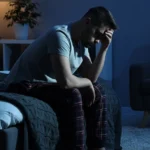 frustrated man sitting on bed at night