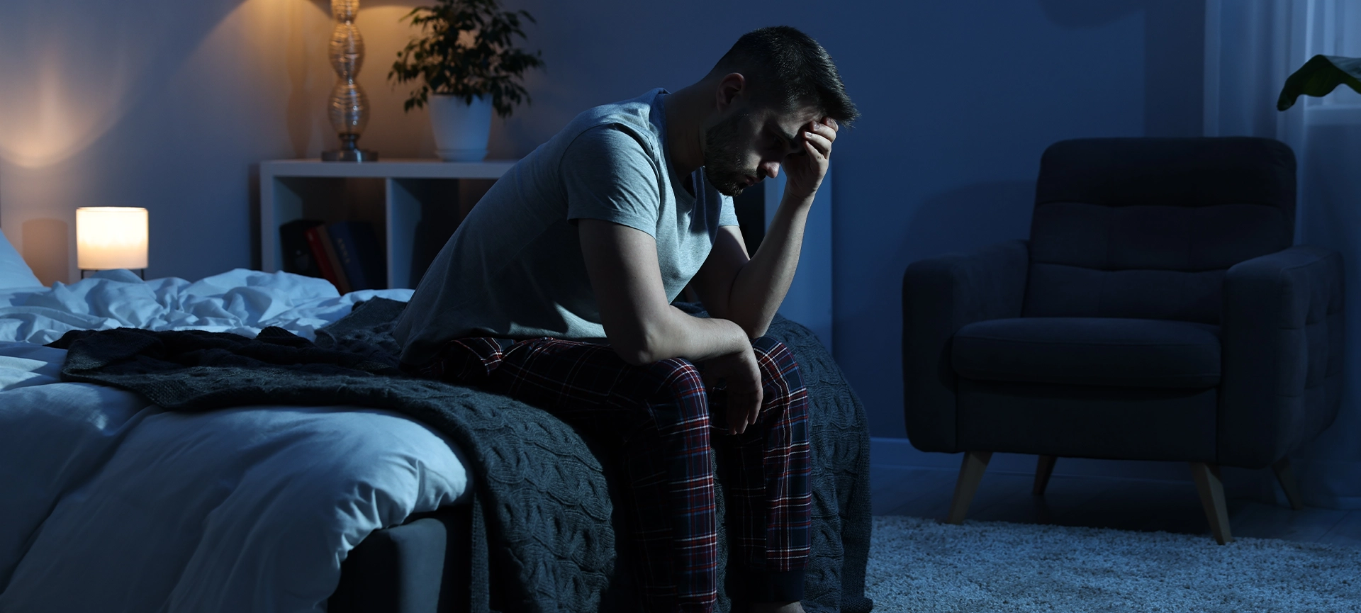 frustrated man sitting on bed at night